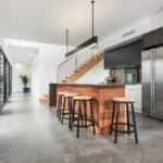 Polished concrete kitchen island with bar stools in modern Perth home interior.