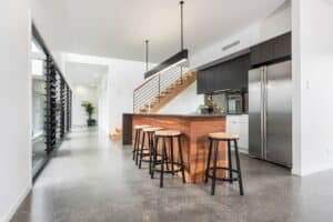 Polished concrete kitchen island with bar stools in modern Perth home interior.